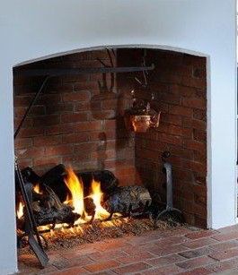 Copper kettle hanging over an open fire in a brick fireplace