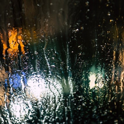 Blurred lights through rain-washed glass