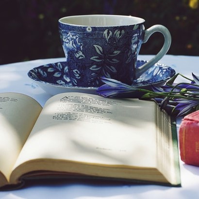 Blue floral tea cup and open book on a table